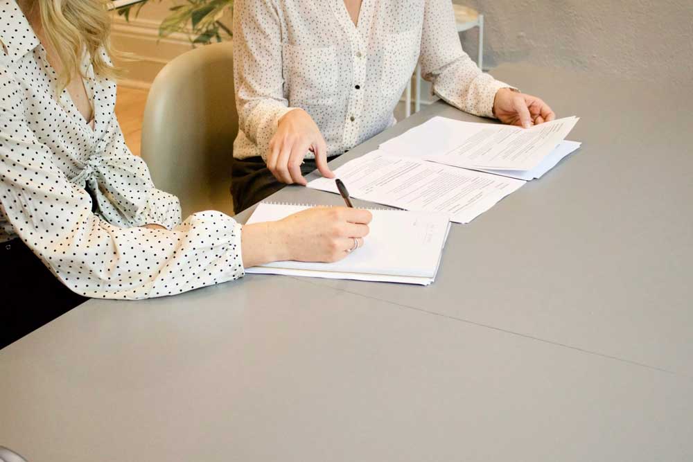 Two women working on bid writing for recruitment contracts